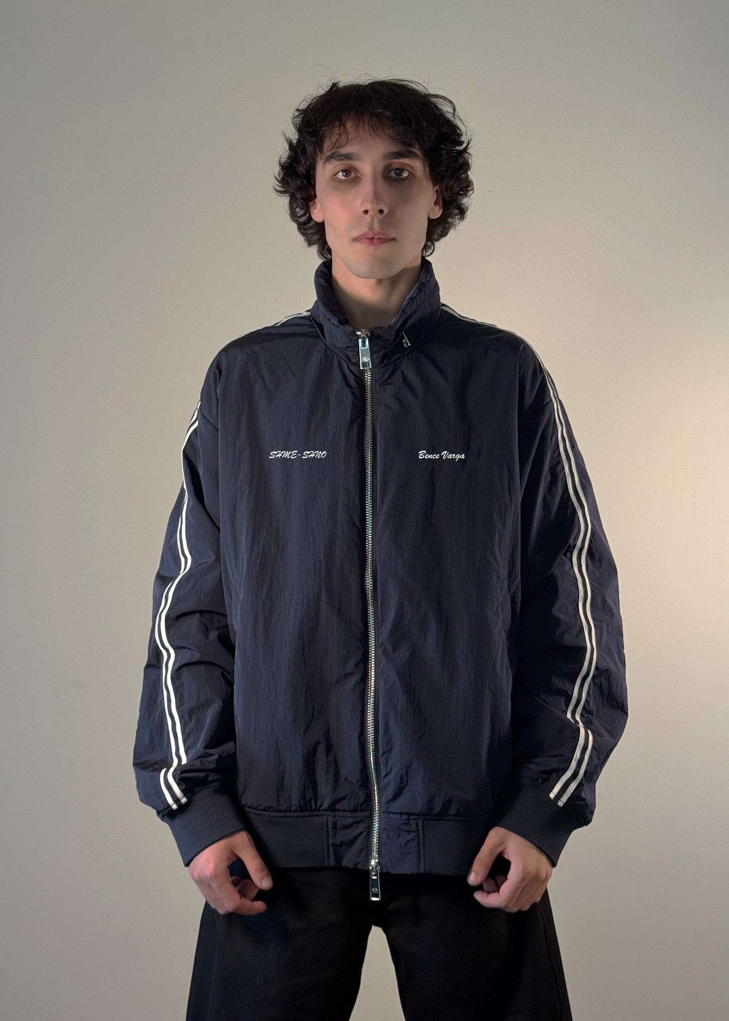 "Men's black track jacket with white stripe sleeves, front zip closure, and embroidered 'SHME-SHNO' and 'Bence Varga' branding – stylish streetwear outerwear for casual fashion."
