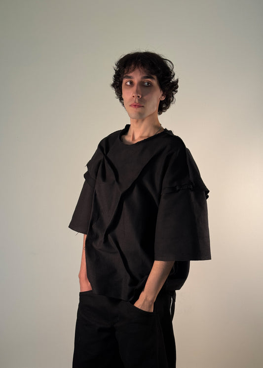 SHTAPPED T-Shirt, Shme-Shno, Budapest-born, Toronto-based fashion brand, distressed black oversized shirt, avant-garde fashion, genderless streetwear, raw hem details, cut-out seams, sculptural silhouette, deconstructivist fashion, varrni sewing technique, stapled design, heavyweight premium cotton, brutalist design, minimalist aesthetics, high-fashion streetwear, anti-fashion, experimental clothing, art-inspired garments, limited edition fashion, underground designer clothing, rare fashion piece